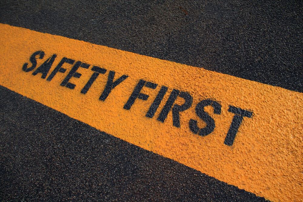 "SAFETY FIRST" painted on pavement with yellow highlight