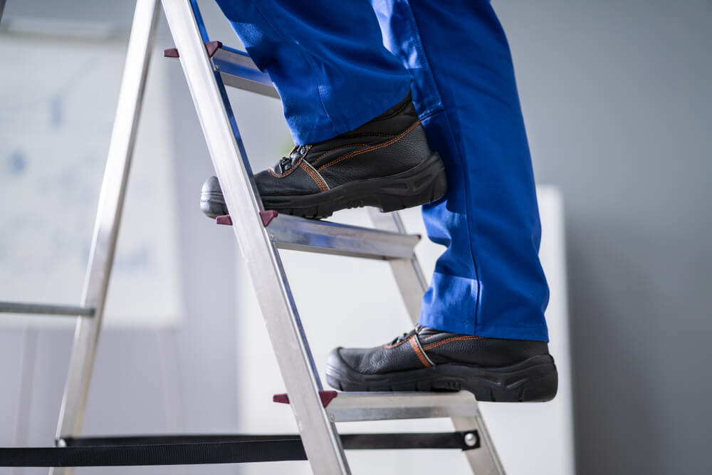 man in blue pants ascending a ladder