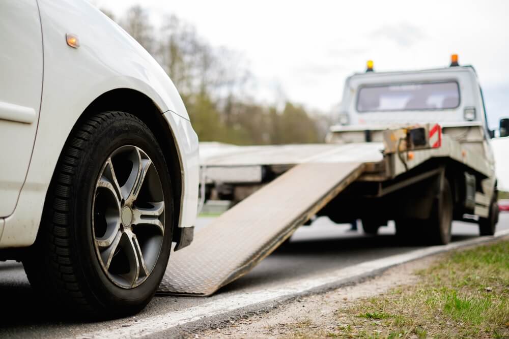 white car being towed by tow truck