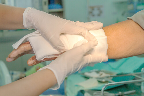 healthcare worker's hands applying gauze to a patient's wrist and forearm burn