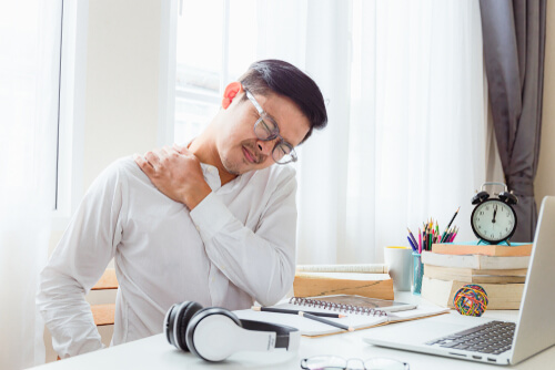 man holding his neck and shoulder wincing in pain