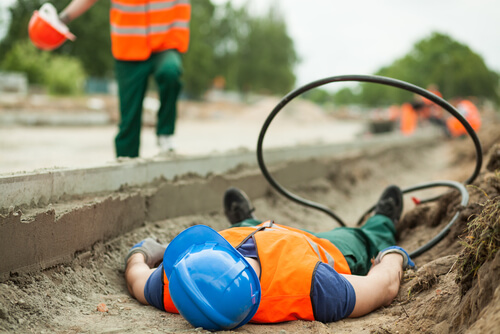 construction worker lying on ground of jobsite with wires nearby