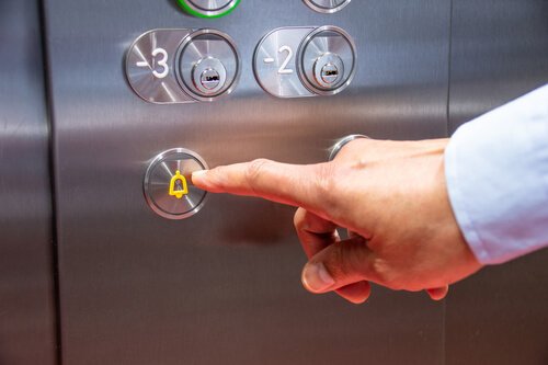 hand pushing the alarm button in an elevator