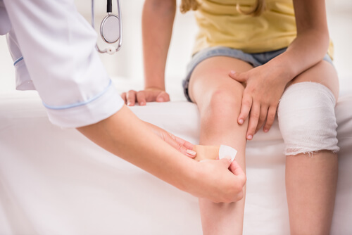 nurse bandaging a child's knee