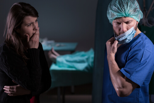 female looking concerned toward a surgeon looking away and removing his face mask
