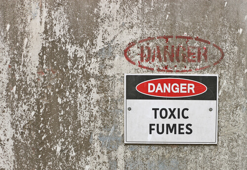 sign that reads 'DANGER' 'TOXIC FUMES' posted to a cement wall