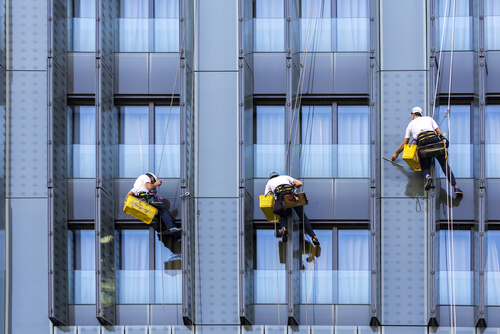three man using suspension devices to clean a NYC highrise window