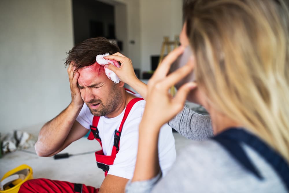 construction with significant head trauma in pain while another worker calls 911 in Queens, NY