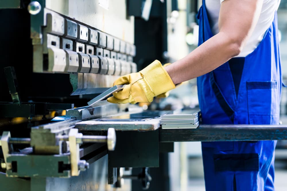 employee using a press machine at work, wearing proper PPE to avoid a crush injury