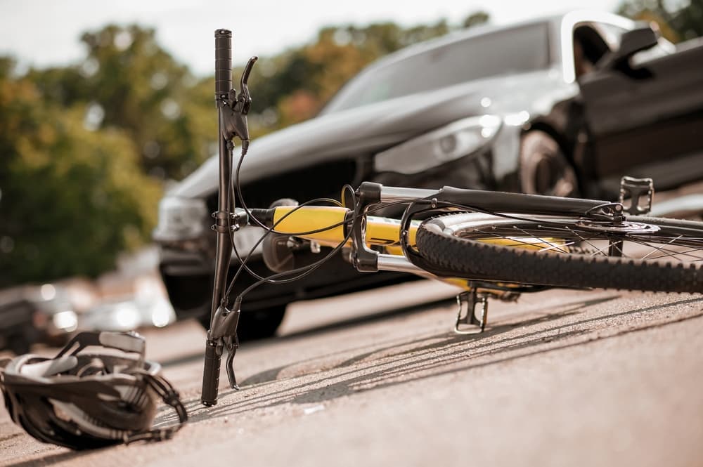 black car that hit bicycle now lying on ground, who is at fault if the bicyclist did not stop at the stop sign?