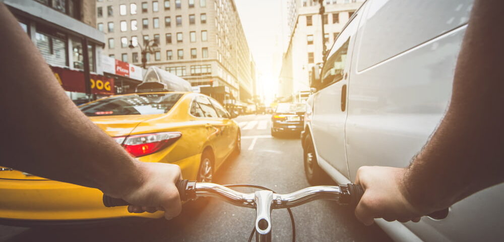 set of hands steering a bicycle through traffic in city street