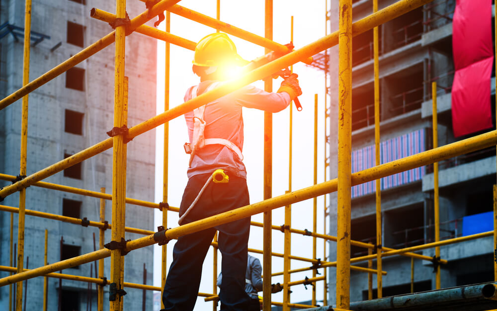 Construction worker wearing safety belt working on scaffolding