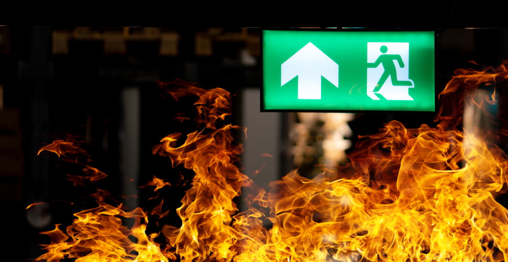 green and white lit exit sign in front of fire