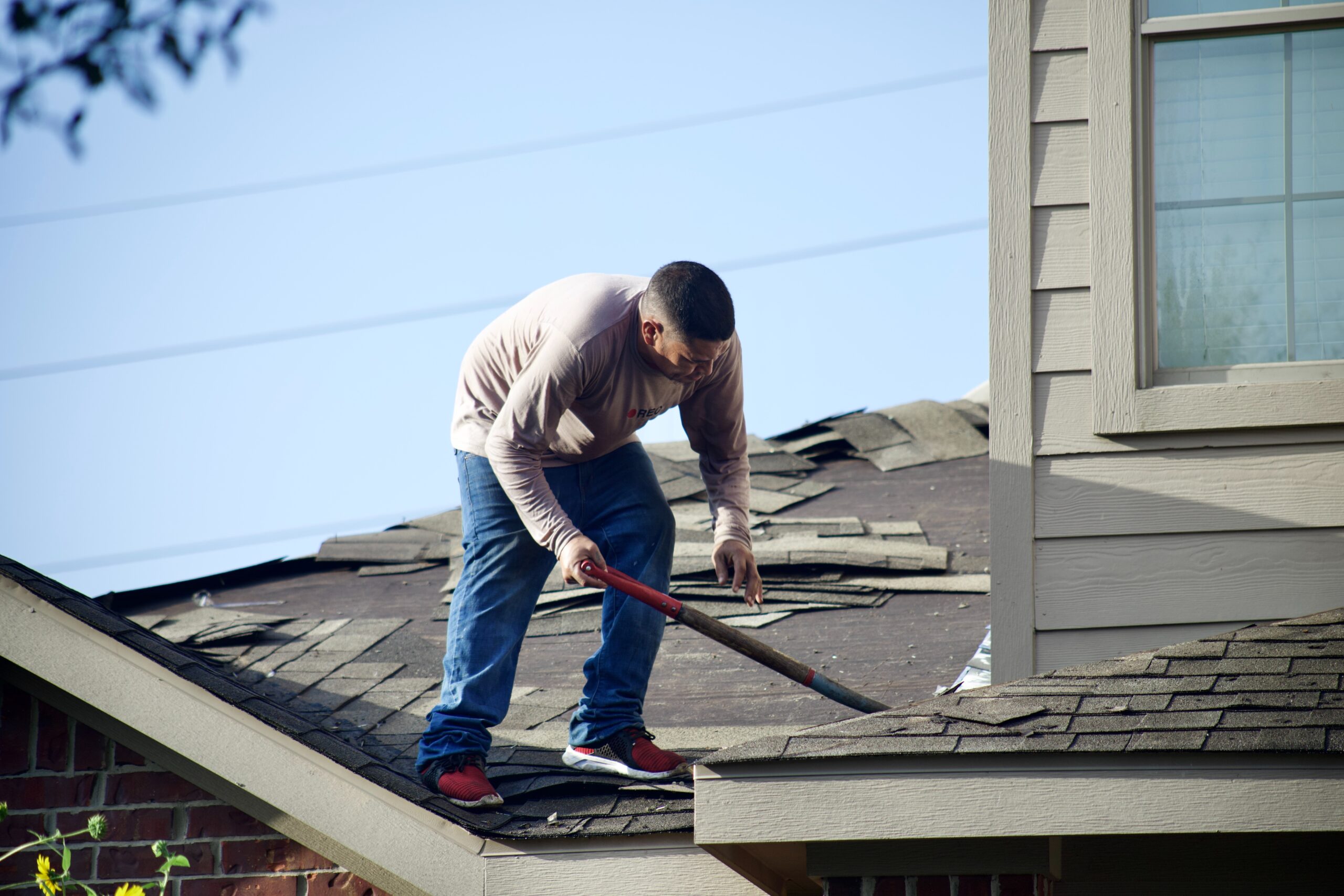 roofer working on residential roof laying shingles