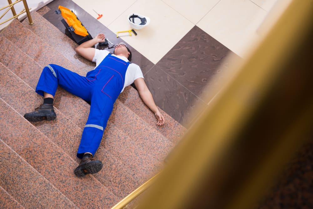 worker in blue overalls lying on the steps after falling