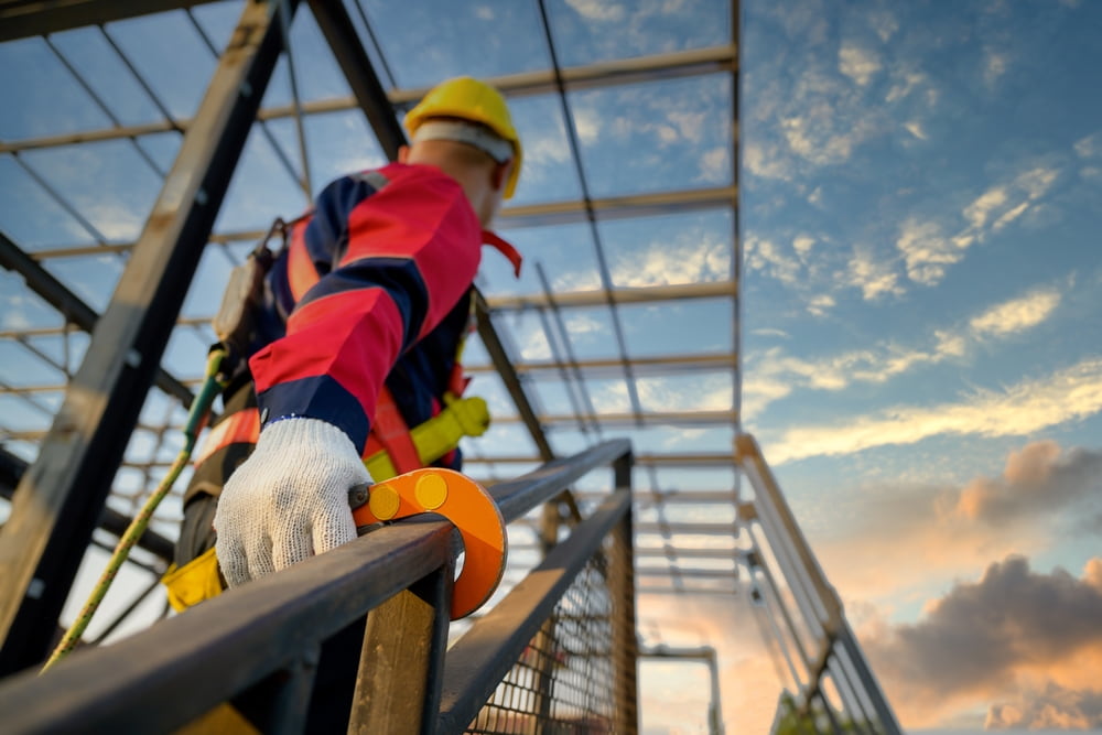 construction worker with safety harness on climbing stairs on a jobsite