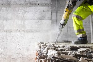 construction worker using tool to break up cement