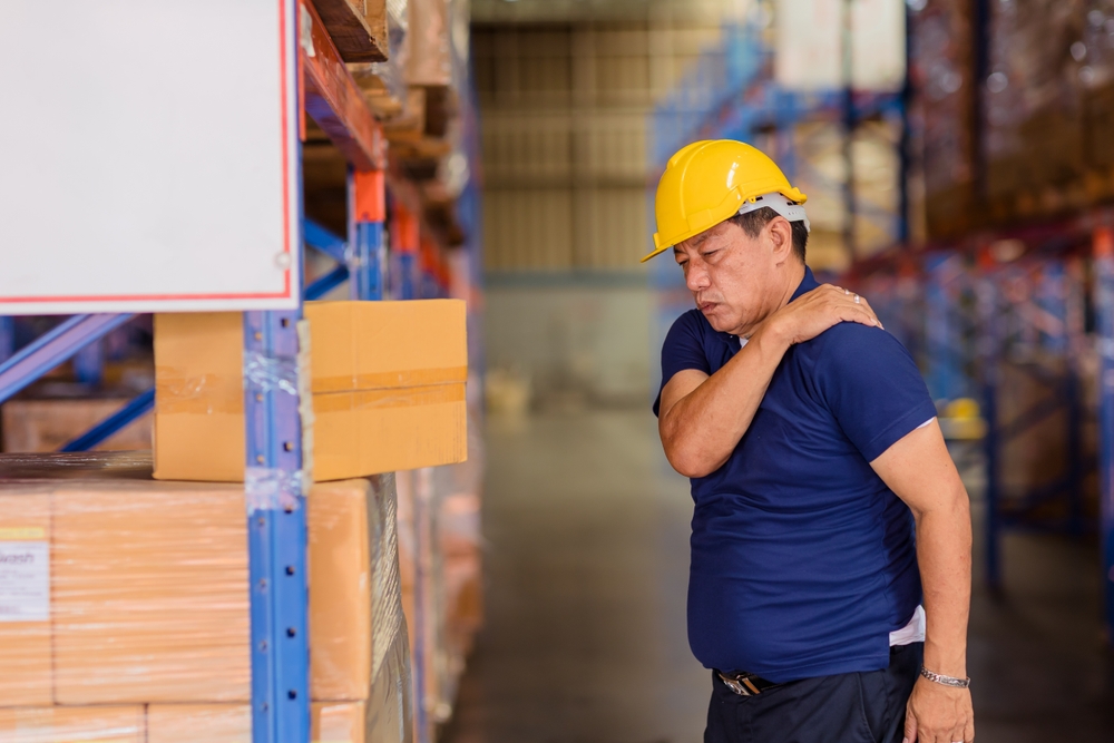 warehouse worker holding back of shoulder and neck in pain