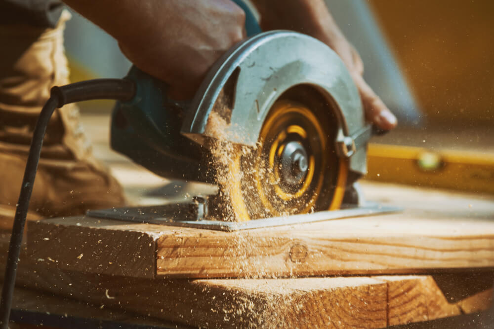 Close-up of a carpenter using a circular saw to cut a large board of wood.