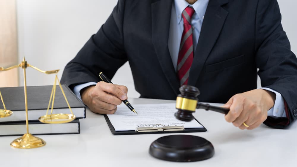A professional lawyer working in his office, reviewing and signing a contract. Providing client consultation on trust law, notary services, and legal solutions.