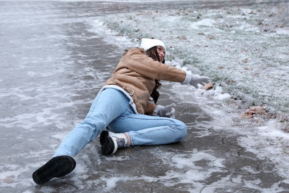Young woman slipped and fell on an icy, slippery pavement outside.