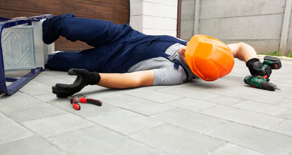 A worker falling from a ladder while working near a house.