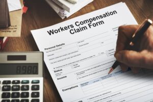 Work Injury Compensation Claim Form Concept: A neatly arranged desk with a partially completed claim form, a pen, and documents symbolizing the process of filing for compensation after a workplace injury.