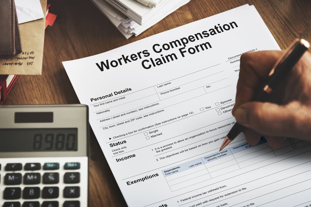 Work Injury Compensation Claim Form Concept: A neatly arranged desk with a partially completed claim form, a pen, and documents symbolizing the process of filing for compensation after a workplace injury.