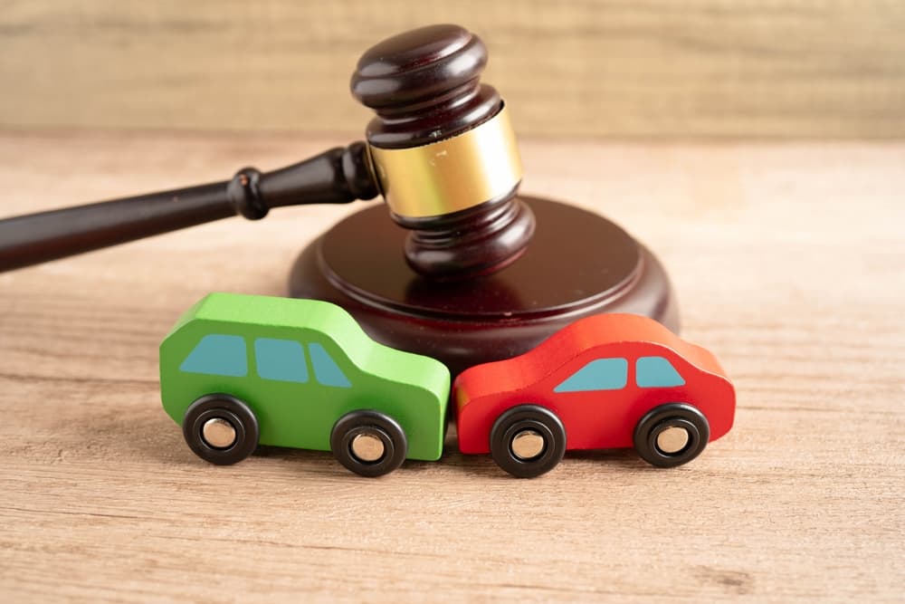 A judge's gavel rests beside a car model, symbolizing car accident lawsuits, insurance claims, and legal proceedings.