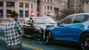 Severe car accident on a busy city street—damaged vehicles, shattered windshields, and debris scattered. Bystanders call for help.