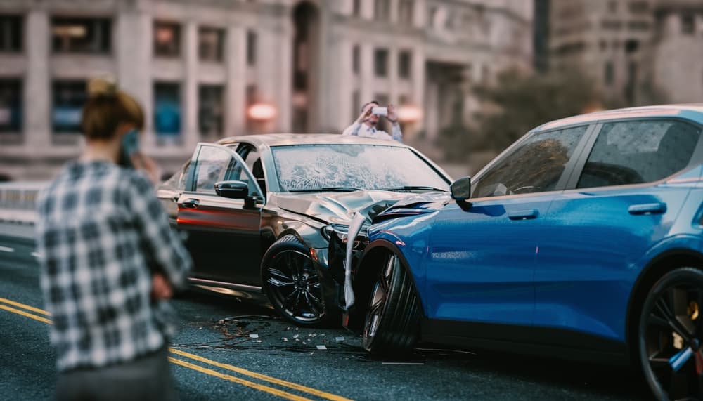 Severe car accident on a busy city street—damaged vehicles, shattered windshields, and debris scattered. Bystanders call for help.