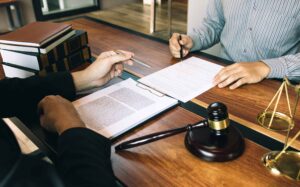 Lawyer consulting with client and reviewing legal documents in office with gavel and justice scales.
